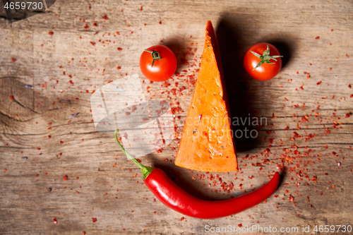 Image of Funny face made of a piece of red gourmet cheese, tomatos and cayenne