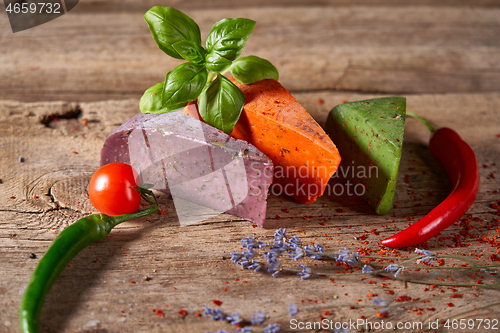 Image of Three different cheeses on rough wooden planks: lavender, paprika and pesto cheeses