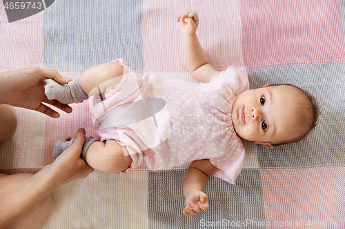 Image of baby girl lying on blanket and mother\'s hands