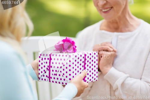 Image of daughter giving present to senior mother at park