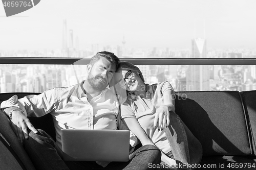 Image of couple relaxing at  home using laptop computers