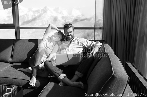 Image of couple relaxing at  home using laptop computers