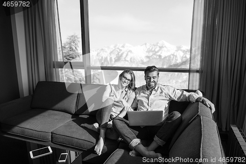 Image of couple relaxing at  home using laptop computers