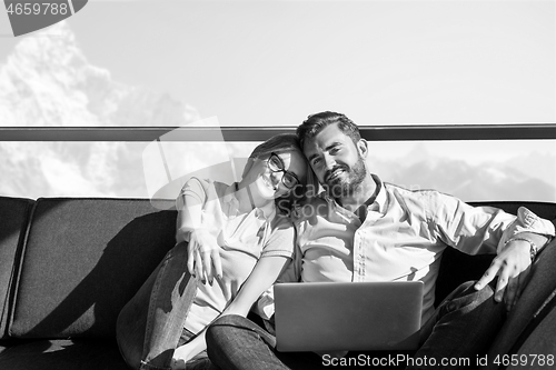 Image of couple relaxing at  home using laptop computers