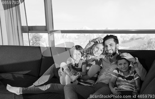 Image of happy young couple spending time with kids at home