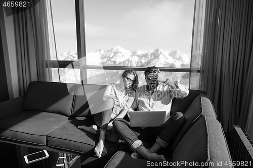 Image of couple relaxing at  home using laptop computers