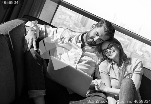 Image of couple relaxing at  home using laptop computers