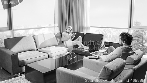 Image of couple relaxing at  home using tablet and laptop computers