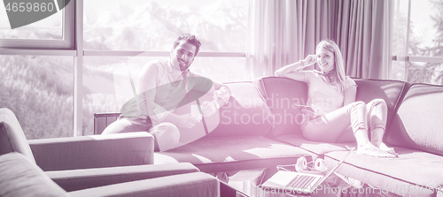 Image of couple relaxing at  home using tablet computer