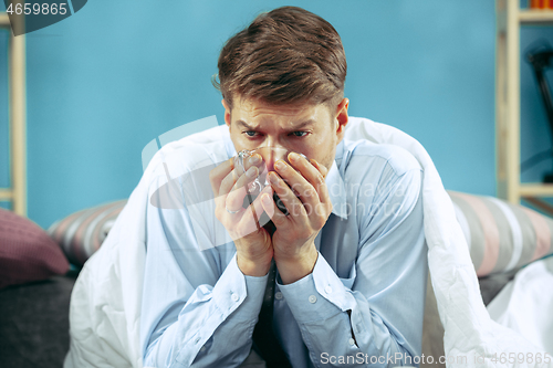 Image of Bearded sick man with flue sitting on sofa at home. Illness, influenza, pain concept. Relaxation at Home. Healthcare Concepts.