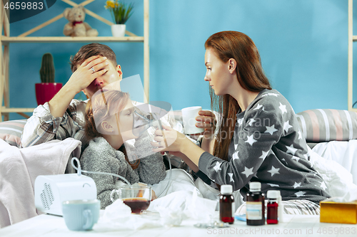 Image of The young parents with sick daughter at home. The ill family.