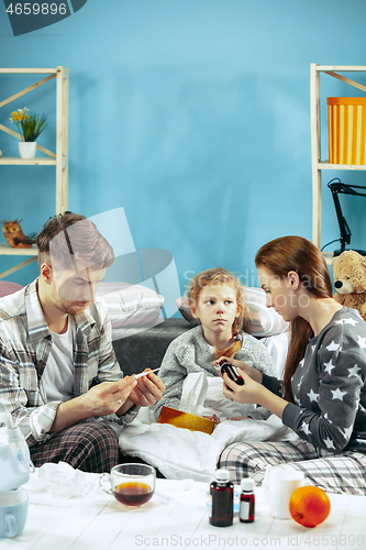 Image of The young parents with sick daughter at home. The ill family.