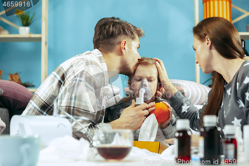 Image of The young parents with sick daughter at home. The ill family.