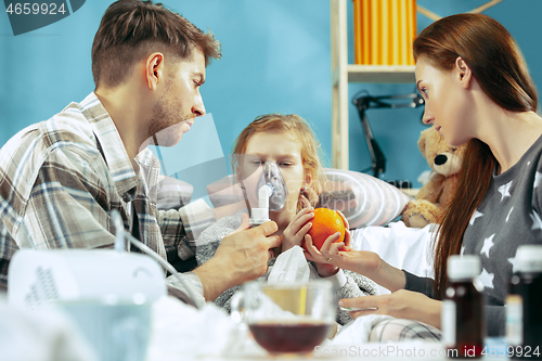 Image of The young parents with sick daughter at home. The ill family.