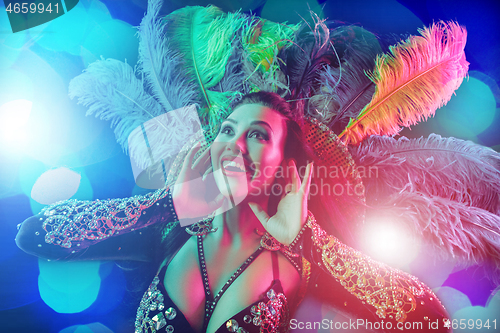 Image of Beautiful young woman in carnival peacock costume