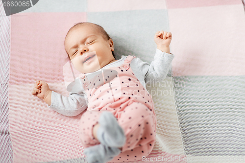 Image of sleeping baby girl in pink suit lying on blanket