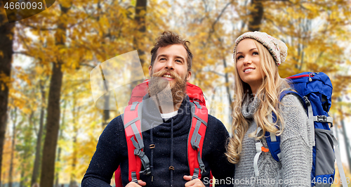 Image of smiling couple with backpacks hiking in autumn