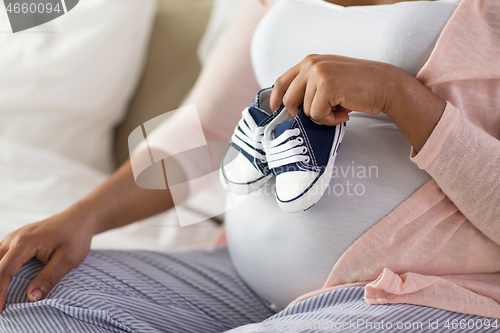 Image of pregnant african woman with little baby bootees