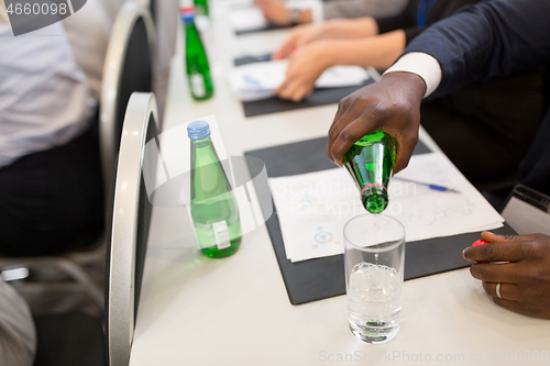 Image of businessman pouring water to glass at conference