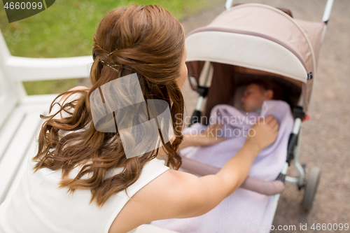 Image of mother with child in stroller at summer park