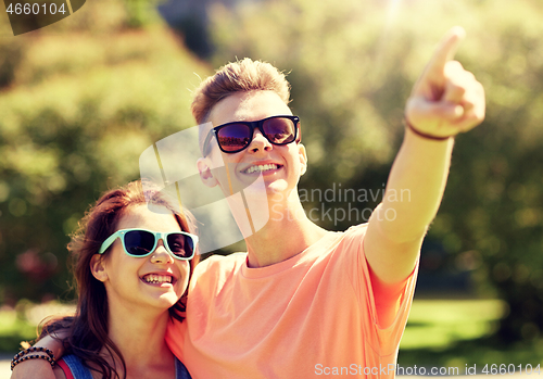 Image of happy couple pointing finger at summer park