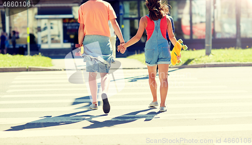 Image of teenage couple with skateboards at city crosswalk
