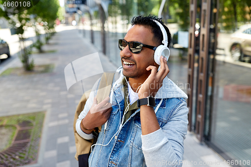 Image of indian man in headphones with backpack in city