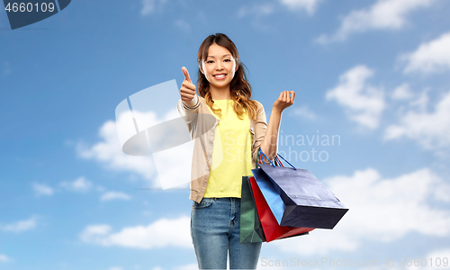 Image of asian woman with shopping bags showing thumbs up