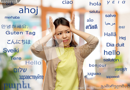 Image of stressed asian woman holding to her head