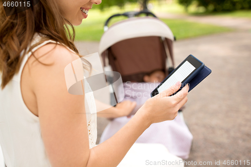 Image of mother with stroller reading internet book at park