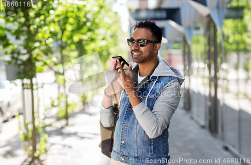 Image of man recorving voice message on smartphone in city