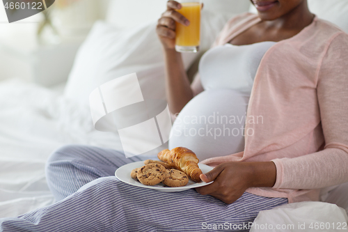 Image of pregnant woman having breakfast in bed at home