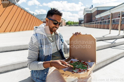 Image of indian man eating takeaway pizza on roof top