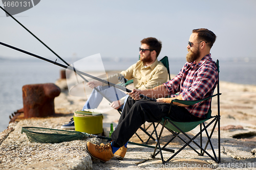 Image of happy friends with fishing rods on pier