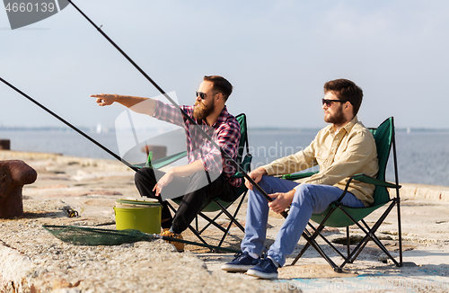 Image of male friends with fishing rods on pier