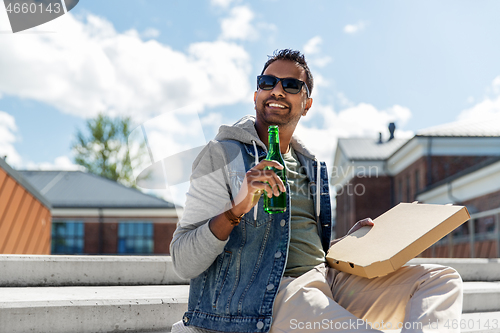 Image of indian man with pizza and drinking beer outdoors