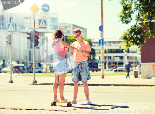 Image of teenage couple riding skateboards on city street