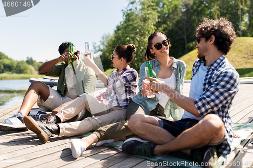 Image of friends drinking beer and cider on lake pier