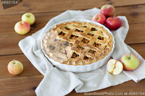 Image of apple pie in baking mold on wooden table