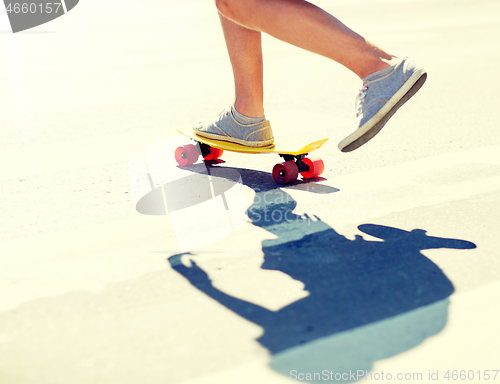 Image of male legs riding short skateboard along crosswalk