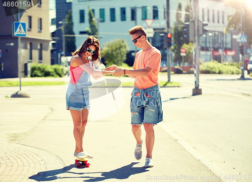 Image of teenage couple riding skateboards on city street