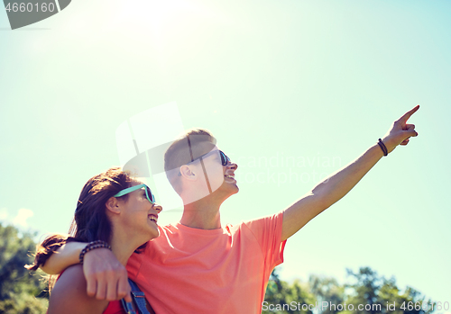 Image of happy couple pointing finger at summer park