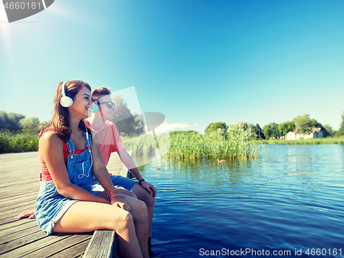 Image of happy teenage couple with earphones on river berth