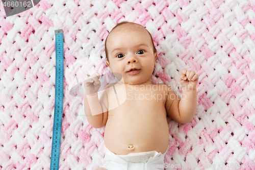 Image of baby girl lying with measure tape on blanket