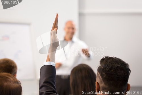 Image of businessman raising hand at business conference