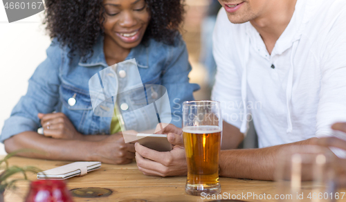 Image of couple with smartphone and beer at bar