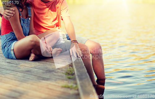 Image of happy teenage couple sitting on river berth