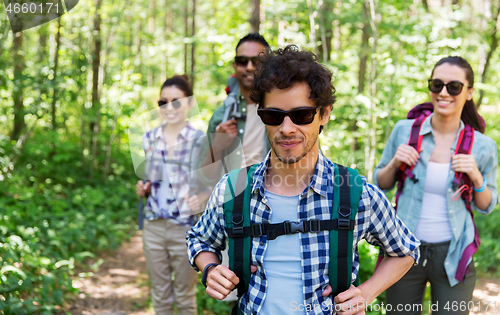 Image of group of friends with backpacks hiking in forest