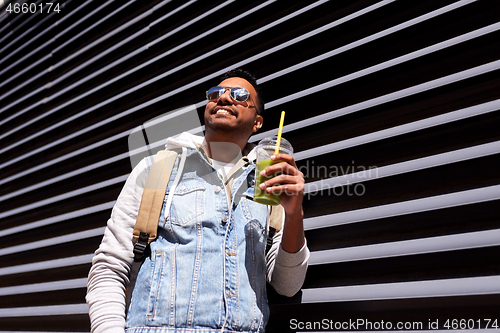 Image of man with backpack drinking smoothie on street