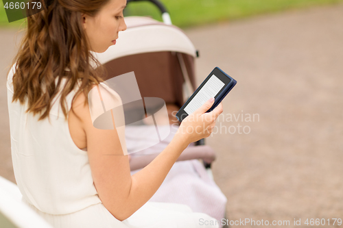 Image of mother with stroller reading internet book at park